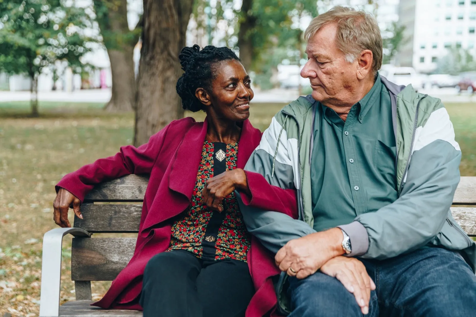 A retired couple laughing together on a park bench
